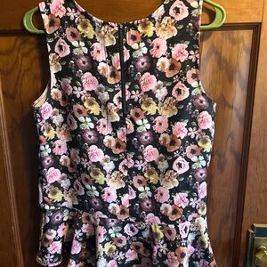 HM black floral sleeveless blouse with bottom ruffle. Zips in back at neck.